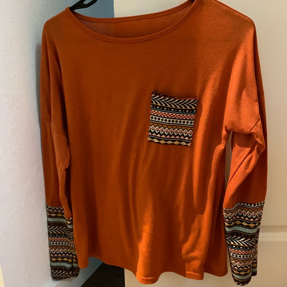 Orange long sleeve shirt with patterned sleeves and pocket.
